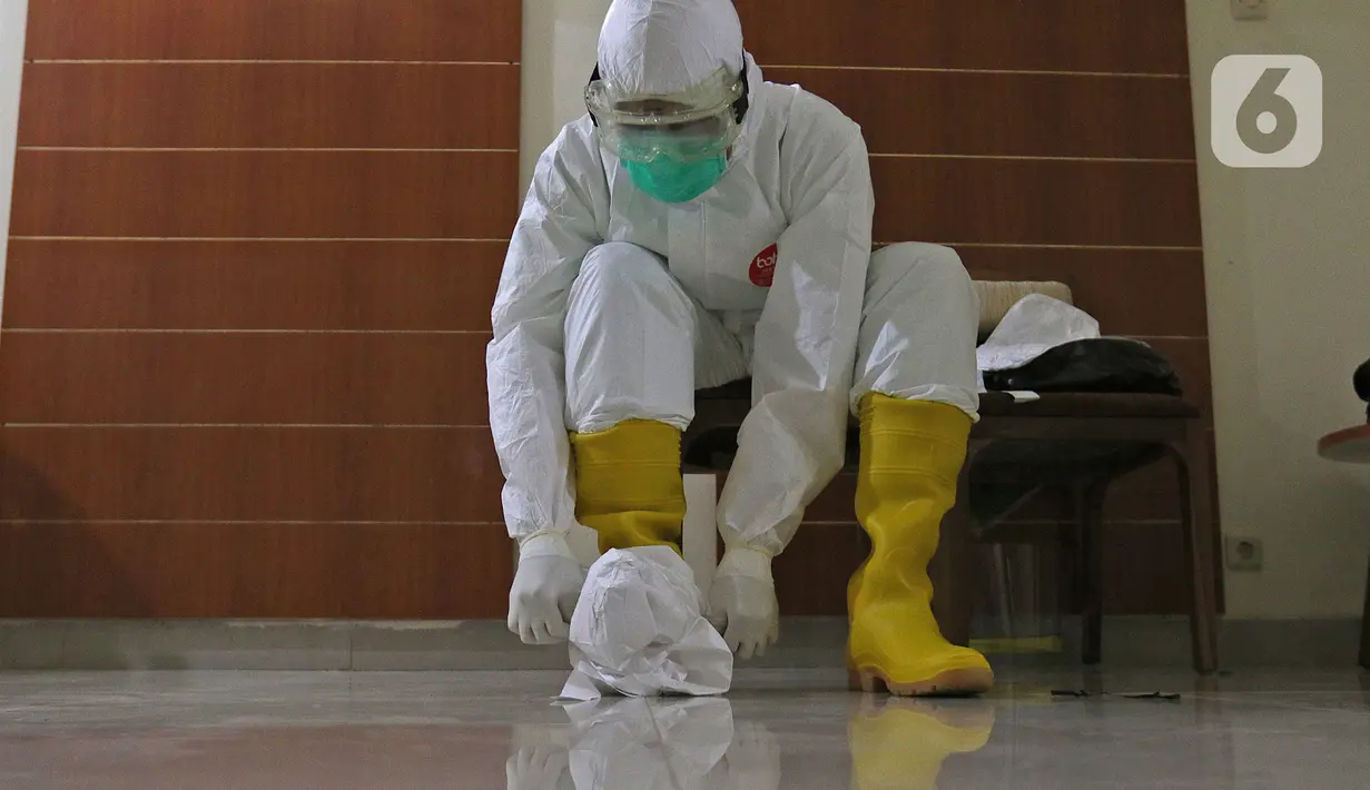 dr Rahmadi Iwan Guntoro, Sp.P membungkus sepatu bootsnya dengan hazmat di Rumah Sakit Haji, Jakarta, Kamis (9/4/2020). Standar APD tingkat perlindungan 3 diperuntukkan untuk ruang prosedur dan tindakan operasi pada pasien dengan kecurigaan atau terkonfirmasi COVID-19. (Liputan6.com/Herman Zakharia)