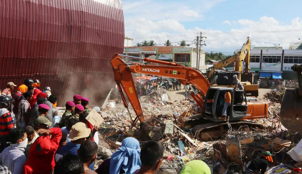 Eskavator membantu mengangkat puing bangunan yang runtuh akibat gempa di Pasar Meureudu, Pidie Jaya, Aceh, Kamis (8/12). Dikabarkan korban meninggal sudah mencapai 102 orang. (Liputan6.com/Angga Yuniar)
