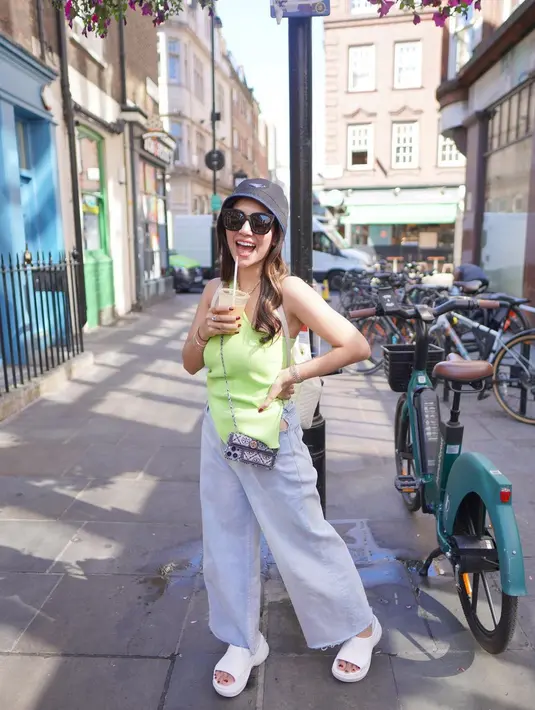 Nisya Ahmad  berpose sambil memegang minuman kopi. Nisya Ahmad melengkapi penampilannya dengan memakai bucket hat Prada, kaca mata hitam dan sandal berwarna putih serta aksesoris lainnya. gaya Nisya terlihat simpel, namun tetap modis. (Instagram/nissyaa)