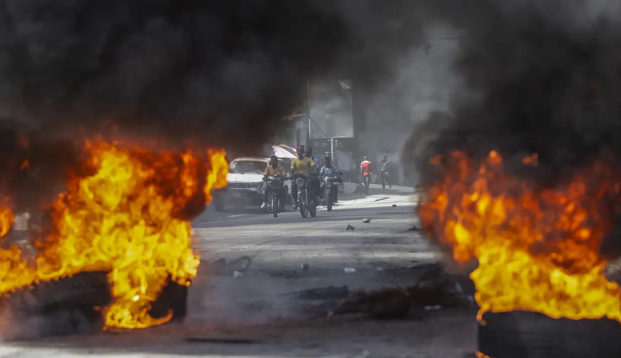 Pengemudi taksi berlari menuju barikade ban yang dibakar pengunjuk rasa saat protes menuntut pembebasan orang-orang yang diculik di Port-au-Prince, Haiti, 25 November 2021. Haiti mengalami peningkatan kasus penculikan terkait geng dan banyak yang menuntut uang tebusan. (AP Photo/Odelyn Joseph)