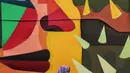Seorang wanita berada di dekat karya seni Mural di TIM, Cikini, Jakarta, Selasa (11/9). Mural tersebut dibuat untuk mempererat kerjasama antara Pemprov DKI Jakarta dengan Kedutaan Besar Kolombia dalam bidang seni perkotaan. (Liputan6.com/Faizal Fanani)