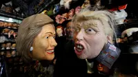Seorang karyawan memegang topeng yang menggambarkan calon presiden Demokrat Hillary Clinton dan calon presiden dari partai Republik Donald Trump untuk menyambut Hallowen disebuah toko mainan di Los Angeles, California, AS (26/10). (Reuters/Mario Anzuoni)
