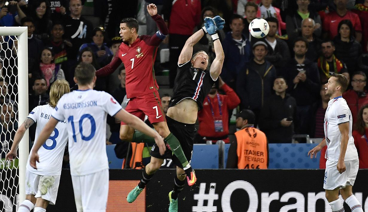Kiper Islandia, Hannes Halldersson, menepis sundulan bintang Portugal, Cristiano Ronaldo, pada laga Grup F Piala Eropa di Stadion Geoffroy Guichard, St Etienne, Rabu (14/6/2016). Islandia bermain imbang 1-1 dengan Portugal. (AFP/Jeff Pachoud)