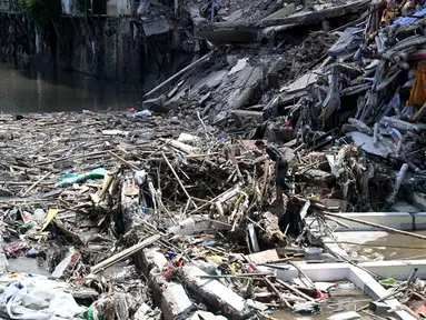 Seorang pria berjalan di atas puing-puing bangunan yang runtuh akibat banjir di Denpasar, Bali, pada Jumat 12 September 2025. (SONNY TUMBELAKA/AFP)