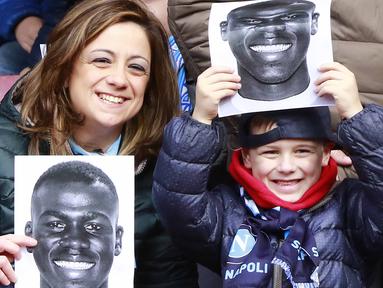 Ibu dan anak memegang poster pemain Napoli, Kalidou Koulibaly pada laga  Serie A Liga Italia di San Paolo stadium, Minggu (7/2/2016).  Kalidou mendapat dukungan atas tindakan rasis dari fans Lazio. (AFP/Carlo Hermann)