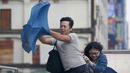 Dua orang memegang payung sambil berjalan menghindari angin kencang yang disebabkan topan Dujuan di Taipei, Taiwan, Senin (28/9). Ribuan orang diungsikan untuk menghadapi topan raksasa Dujuan yang diprediksikan akan menyerang Taiwan.(REUTERS/Pichi Chuang)