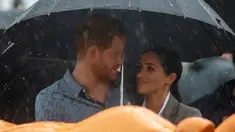 Pangeran Harry dan Meghan Markle berlindung di bawah payung saat piknik di Victoria Park, Dubbo, Australia, Rabu (17/10). Ini adalah hari kedua Pangeran Harry dan Meghan Markle dalam kunjungannya ke Australia. (Ian Vogler/Pool via AP)