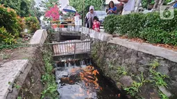 Warga bersama anak-anak melihat ikan yang dibudidaya di sepanjang saluran air di Puri Pamulang, Tangerang Selatan, Minggu (13/8/2020). Saluran air atau selokan dari aliran Situ Ciledug dimanfaatkan warga sejak PSBB diterapkan pemerintah. (Liputan6.com/Fery Pradolo)