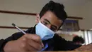 Seorang siswa yang mengenakan masker mengikuti ujian di sebuah sekolah di Sanaa, Yaman (30/8/2020). (Xinhua/Mohammed Mohammed)