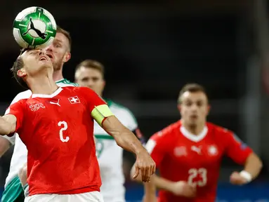 Pemain Swiss, Stephan Lichtsteiner menyundul bola pada leg kedua fase playoff Piala Dunia 2018 zona Eropa melawan Irlandia Utara di St Jakob Park Stadium, Minggu (12/11). Swiss akhirnya lolos ke putaran final Piala Dunia. (Peter Klaunzer/Keystone via AP)