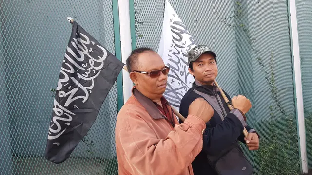 Dua pria penjemput Ahmad Dhani membawa bendera tauhid