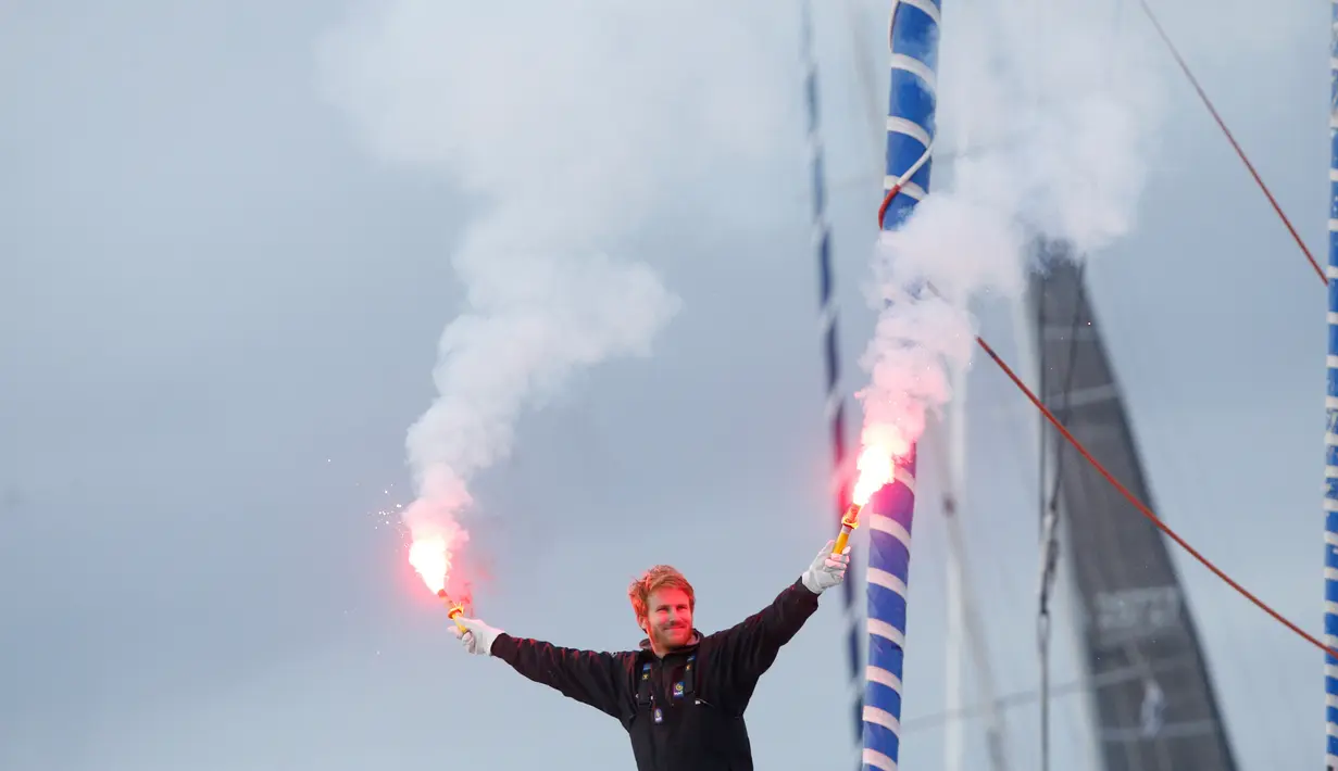 Pelaut Prancis, Francois Gabart menyalakan flare di atas kapal Macif saat merayakan rekor dunianya di pelabuhan Brest, Minggu (17/12). Gabart melintasi garis finis di bagian barat batas perairan Inggris dan Prancis pada Minggu pagi. (AP/Thibault Camus)