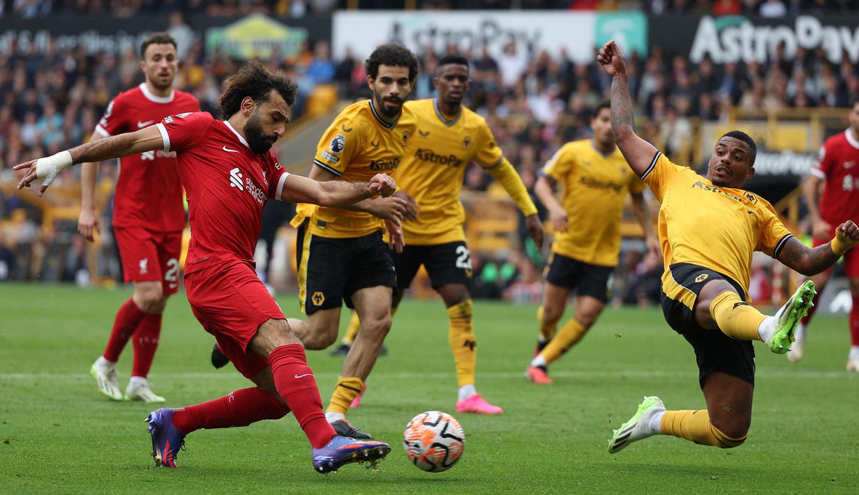 Striker Liverpool, Mohamed Salah (kiri) melepaskan umpan yang akhirnya menghasilkan gol pertama yang dicetak Cody Gakpo pada laga pekan kelima Premier League 2023/2024 di Molineux Stadium, Wolverhampton, Sabtu (16/9/2023) malam WIB. (AFP/Adrian Dennis)