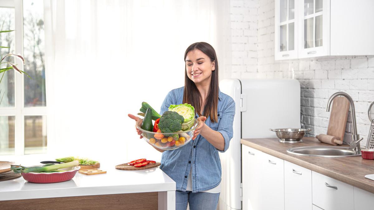 Девушка с овощами. Женщина ест овощи стоковые. Women in the Kitchen stock photo.
