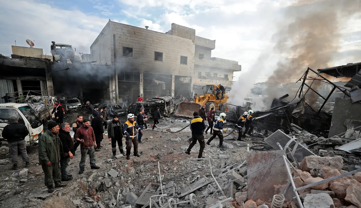 Anggota Syrian Civil Defence atau White Helmets memadamkan api di lokasi serangan udara rezim di Idlib, Suriah, Rabu (15/1/2020). Serangan udara yang dilancarkan pasukan pemerintah menghantam pasar sayur-mayur dan toko-toko reparasi di Idlib. (Omar HAJ KADOUR/AFP)