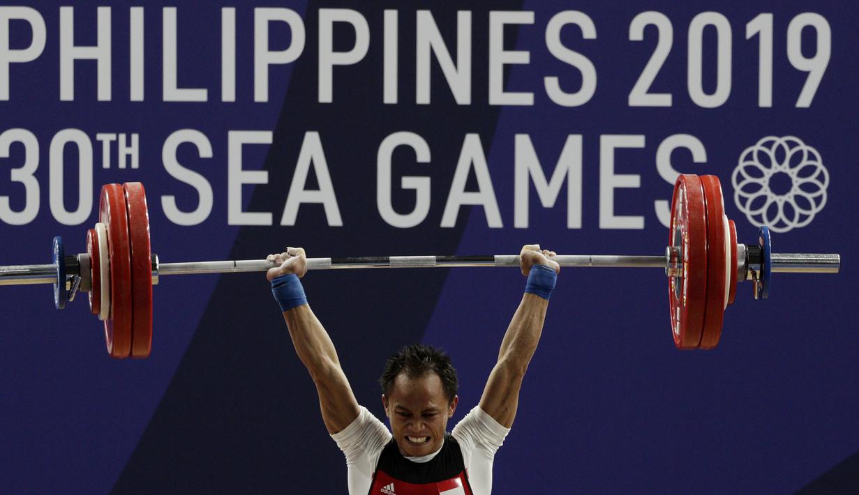 Lifter Suratman melakukan angkatan saat SEA Games 2019 cabang angkat besi nomor 55 kg di Stadion Rizal Memorial, Manila, Minggu (1/12). Dirinya meraih perak dengan total angkatan 250 kg. (Bola.com/M Iqbal Ichsan)