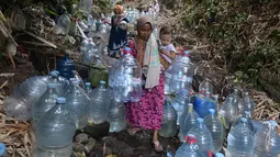 Warga berjalan untuk mengambil air untuk minum dan kebutuhan mck rumah  di sumber mata air Sumur Bendung, Gunung Batur, Kota Cilegon, Banten, Minggu, (15/7/2026). (KLY/Arie Basuki)