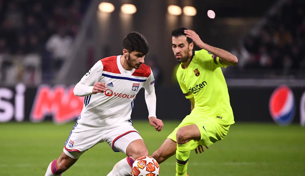 Gelandang Lyon, Martin Terrier melewati Sergio Busquets pada leg 1, babak 16 besar Liga Champions yang berlangsung di stadion Parc Olympique Lyonnais, Lyon, Rabu (20/2). Barcelona bermain imbang 0-0 kontra Lyon. (AFP/Franck Fife)