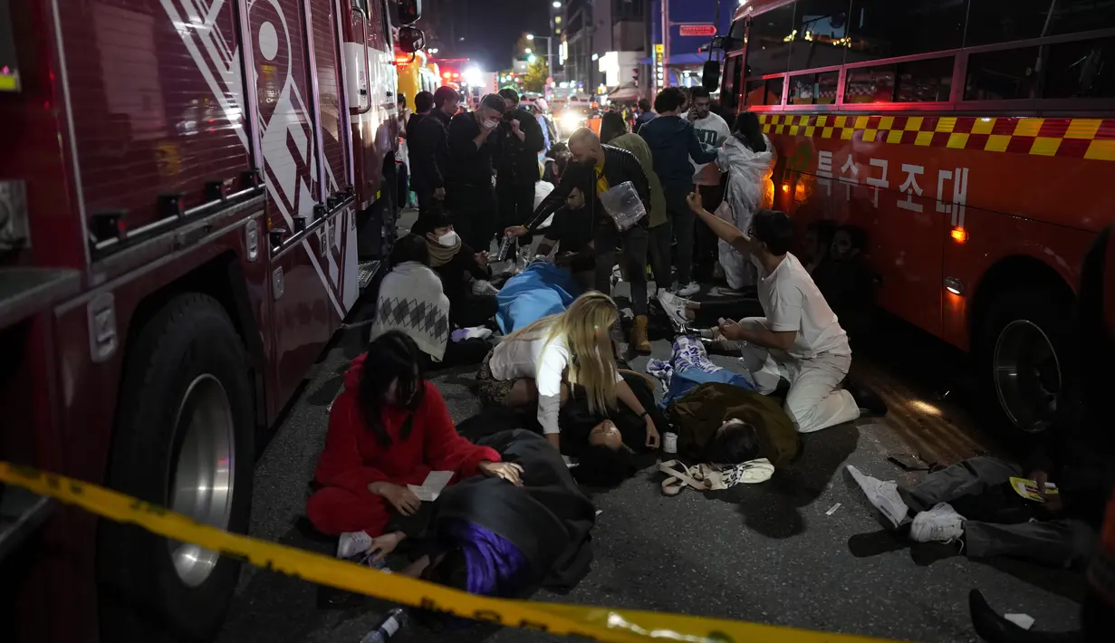 Orang-orang yang terluka ditolong di jalan dekat tempat kejadian di Seoul, Korea Selatan, Minggu pagi (30/10/2022). Puluhan orang mengalami henti jantung setelah ribuan orang berdesakan di sebuah gang di kawasan Itaewon untuk merayakan Halloween pada Sabtu malam. (AP Photo/Lee Jin-man)