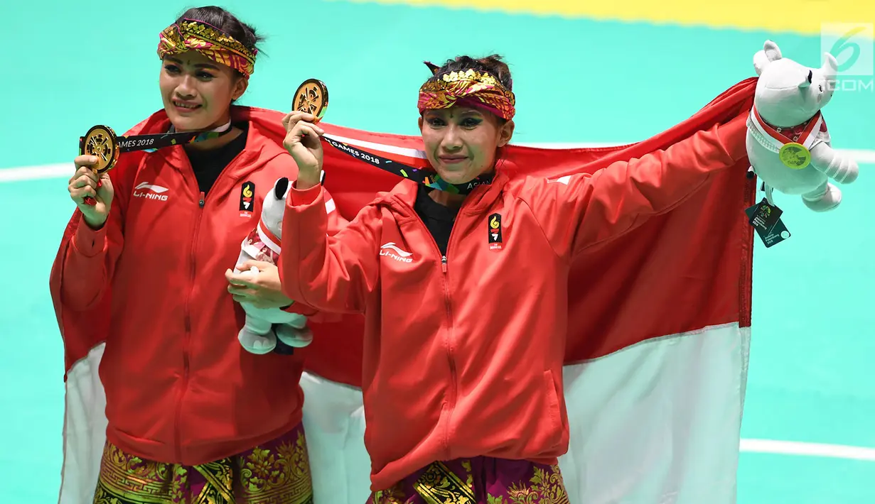 Pasangan pesilat Indonesia, Ayu Sidan Wilantari dan Ni Made Dwiyanti membentangkan bendera merah putih saat merayakan kemenangan usai meraih medali emas nomor seni ganda putri di Padepokan Pencak Silat (TMII, Rabu (29/8). (Merdeka.com/ Imam Buhori)
