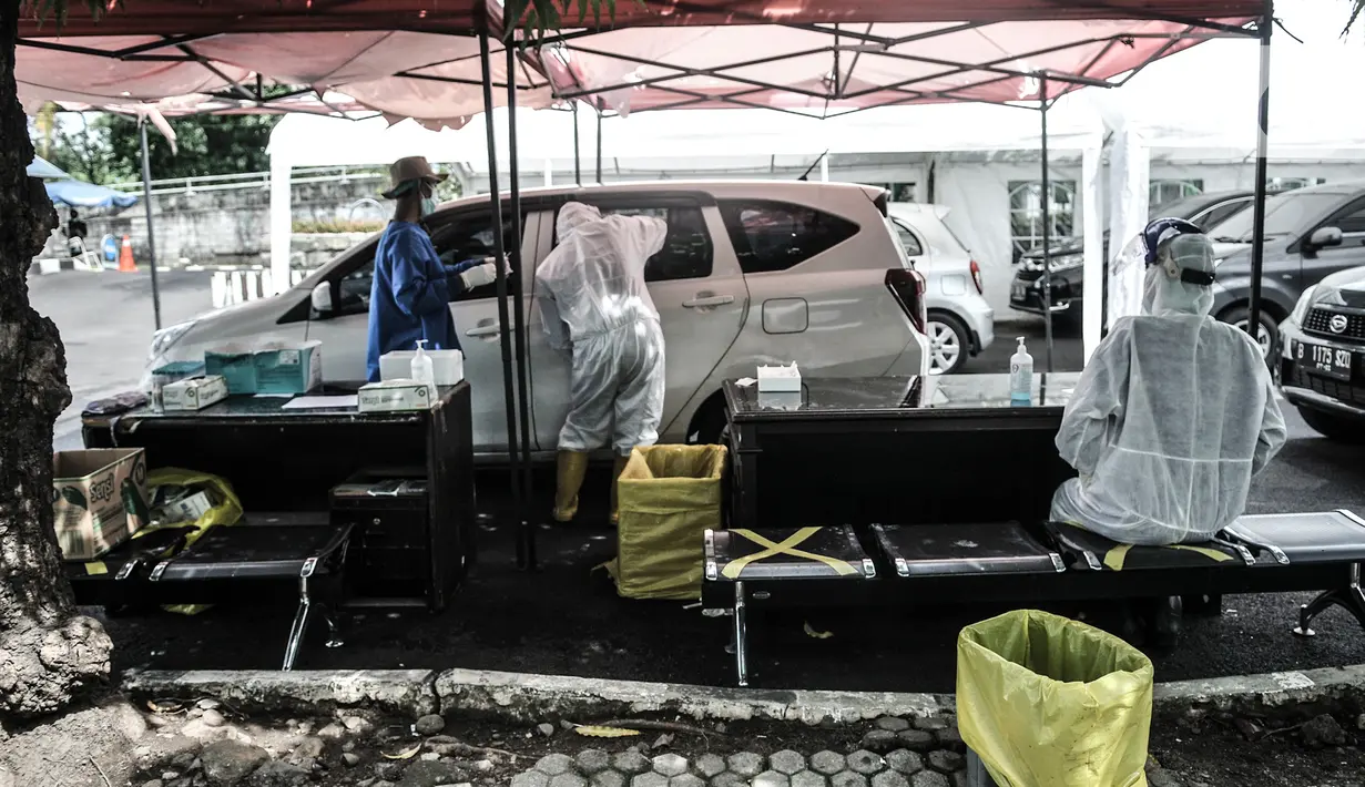 Petugas kesehatan melakukan tes usap PCR drive thru kepada pengguna kendaraan di halaman Rumah Sakit Pertamina Jakarta (RSPJ), Rabu (6/1/2021). RSPJ menyediakan layanan tes usap PCR mandiri secara drive thru guna melacak sekaligus memutus penyebaran Covid-19. (merdeka.com/Iqbal Nugroho)