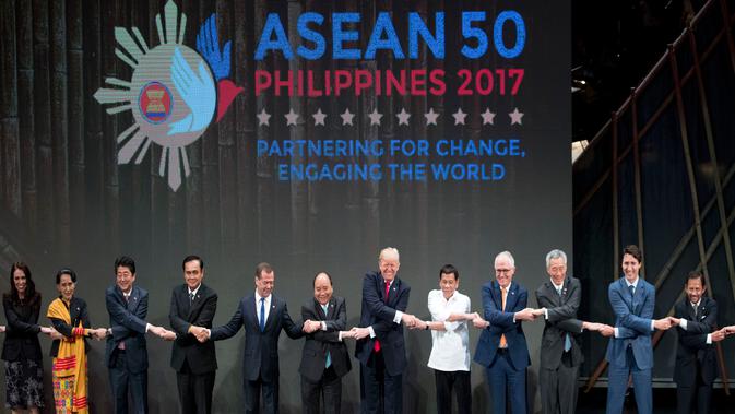 Presiden AS, Donald Trump dan para pemimpin lainnya melakukan salaman khas ASEAN di penghujung upacara pembukaan KTT ASEAN di Manila, Filipina, Senin (13/11). Trump sempat kesulitan menempatkan tangannya di posisi yang pas. (AP/Andrew Harnik)