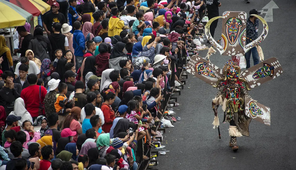 Warga menyaksikan peserta menampilkan kreasi kostum dalam Jember Fashion Carnaval (JFC) di Jember, Provinsi Jawa Timur pada Minggu (4/8/2019). Kegiatan ini mengangkat tema 'tribal grandeur', dengan menghadirkan keagungan 8 suku di dunia. (Photo by JUNI KRISWANTO / AFP)