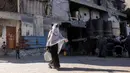 Seorang wanita berjalan dengan wadah air setelah mengisi tangki air di kamp penampungan, Khan Yunis, Jalur Gaza Selatan pada 6 Juni 2026. (Bashar Taleb/AFP)