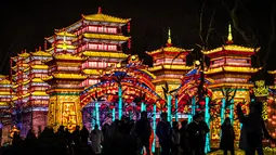 Pengunjung berdiri dekat lentera istana raksasa dalam Festival Lentera Gaillac di Taman Foucaud, Gaillac, Prancis, Rabu (12/12). Festival ini sebagai bagian dari Festival Lentera Tradisional China. (ERIC CABANIS/AFP)