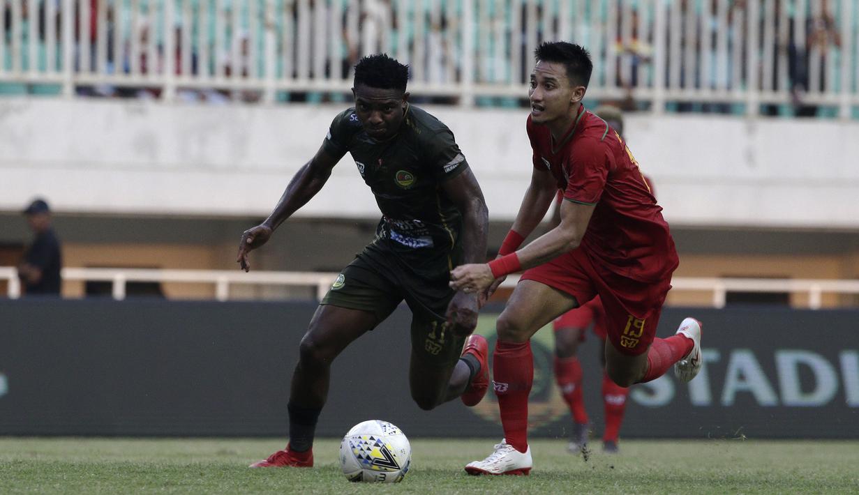 Gelandang Tira Persikabo, Osas Saha, berebut bola dengan bek Kalteng Putra, Dendi Agustan, pada laga Shopee Liga 1 di Stadion Pakansari, Bogor, Jumat (26/7). Tira Persikabo menang 5-2 atas Kalteng. (Bola.com/Yoppy Renato)
