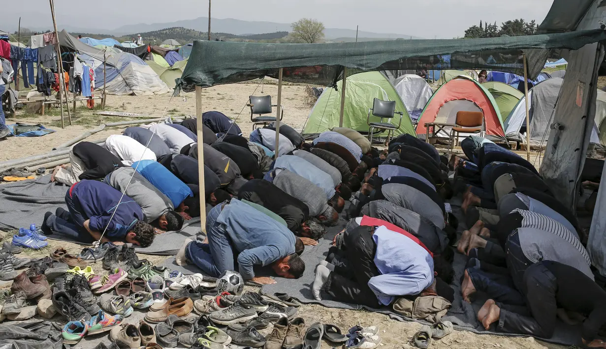 Para imigran terlihat khusyuk saat menggelar salat Jumat di sebuah kamp darurat perbatasan Yunani-Makedonia,desa Idomeni, Yunani (8/4). Meski tengah mencari perlindungan, mereka tak melalaikan kewajibannya sebagai seorang muslim. (REUTERS/Marko Djurica)