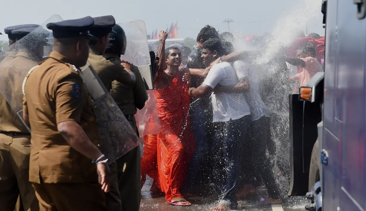 Sejumlah biksu dan aktivis bentrok dengan polisi saat aksi protes di kota pelabuhan selatan Hambantota, Sri Lanka (7/1). Meski warga lokal akan di berikan lahan baru mereka tetap menolak pembangunan zona industri tersebut. (AFP/Ishara S. Kodikara)