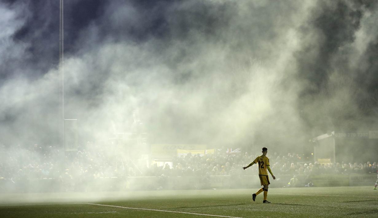 Asap flare yang dinyalakan suporter masuk ke dalam lapangan saat laga Sutton United melawan Arsenal pada putaran kelima Piala FA di Gander Green Lane stadium, London, (20/2/2017). Arsenal menang 2-0. (AP/Matt Dunham)