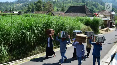 Warga membawa makanan menuju makam Desa Selo, Kabupaten Boyolali, Kamis (3/5). Tradisi ini Sebagai perayaan menyambut datangnya bulan ramadan, kemudian dilanjutkan makan bersama di pertigaan jalan desa. (Liputan6.com/Gholib)