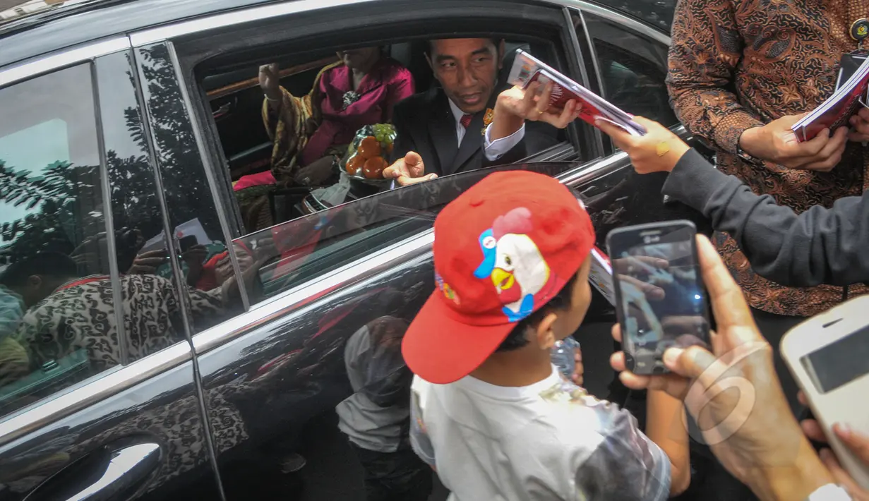 Presiden Joko Widodo saat membagikan buku kepada warga seusai acara makan siang bersama kepala negara serta delegasi negara-negara peserta Konferensi Asia Afrika di Jalan Cicendo, Bandung, Jumat (24/4/2015). (Liputan6.com/Faizal Fanani)