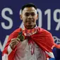 Lifter Eko Yuli menunjukkan medali emas SEA Games 2019 cabang angkat besi nomor 61 kg di Stadion Rizal Memorial, Manila, Filipina, Minggu (1/12/2019). Dirinya meraih emas dengan total angkatan 309 kg. (Bola.com/M Iqbal Ichsan)