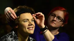 Seorang pegawai tampak merapikan patung salah satu member One Direction, Harry Styles, di museum lilin Madame Tussauds, London, Rabu (6/8/14). (AFP PHOTO/Carl COURT)