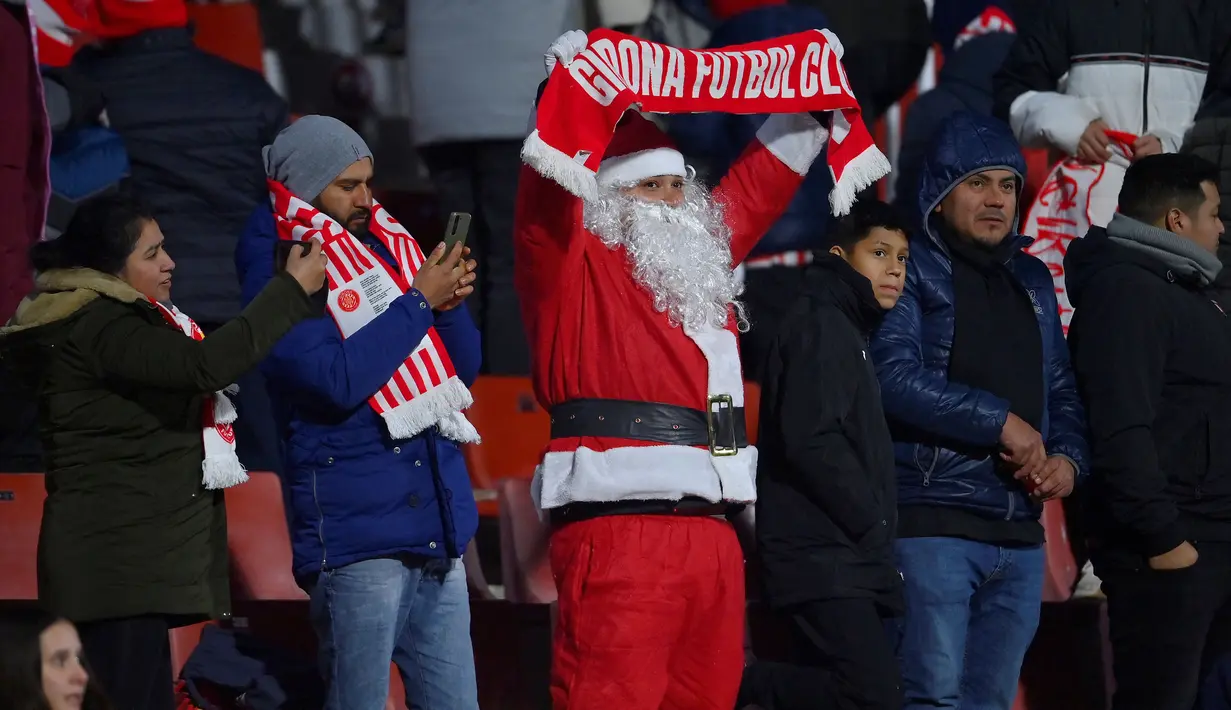 Seorang pendukung Girona dengan mengenakan busana Santa Claus merayakan kemenangan timnya atas Alaves setelah berakhirnya laga pekan ke-17 Liga Spanyol 2023/2024 di Montilivi Stadium, Girona, Selasa (19/12/2023) dini hari WIB. (AFP/Pau Barrena)