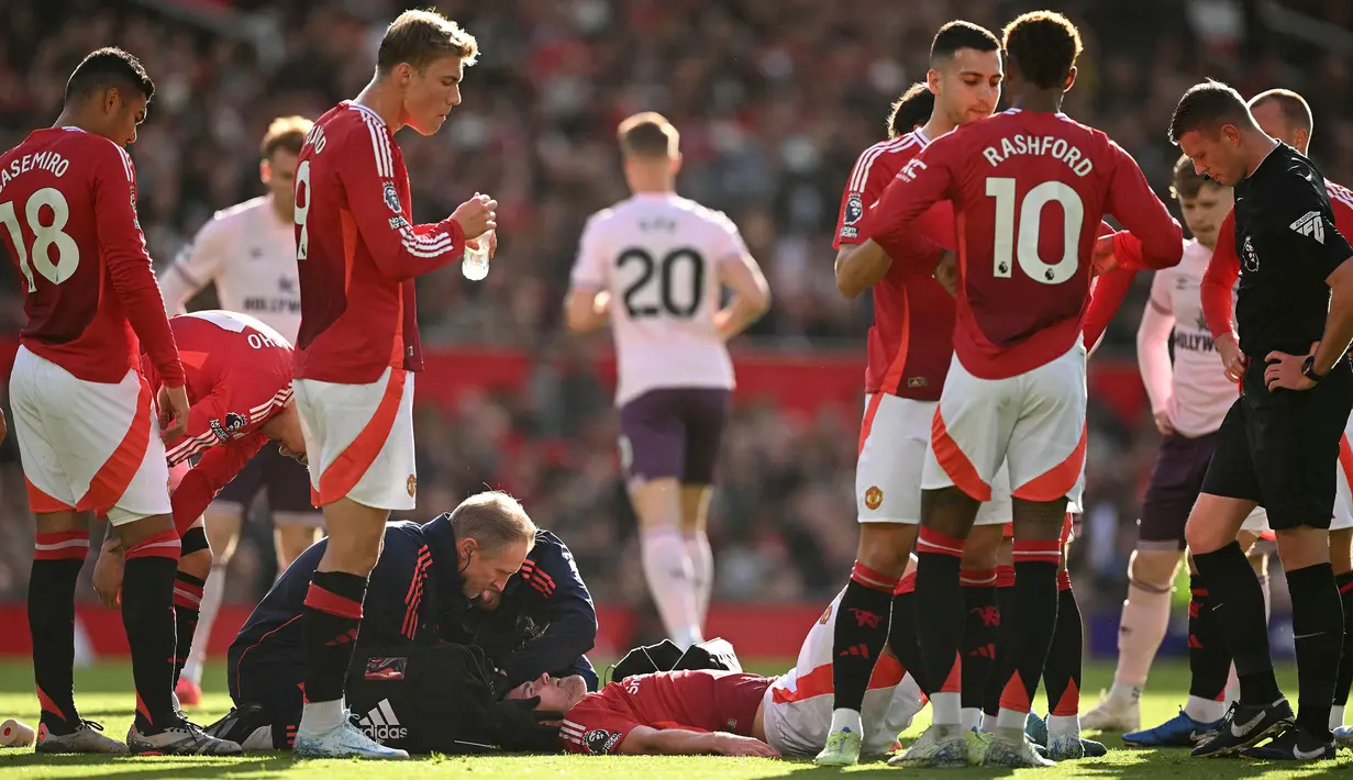 Pemain Manchester United, Matthijs de Ligt mendapatkan perawatan dari tim medis saat kepalanya mengalami pendarahan setelah berbenturan dengan pemain Brentford, Kevin Schade dalam laga lanjutan Liga Inggris 2024/2025 di Old Trafford, Manchester, Sabtu (19/10/2024). (AFP/Oli Scarff)