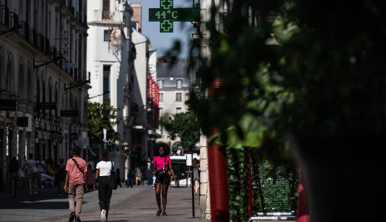 <p>Orang-orang berjalan di jalan saat lampu apotek menunjukkan suhu turun 44 derajat celsius di Nantes, Senin (18/7/2022). Peramal cuaca menempatkan 15 departemen di sebagian besar sisi barat Prancis ke status siaga tertinggi untuk suhu ekstrem saat gelombang panas melanda negara itu dan akan mencapai puncaknya. (Loic VENANCE / AFP)</p>