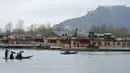 Seorang awak perahu Kashmir mengangkut penumpang saat hujan di Danau Dal di Srinagar (20/3). Danau Dal yang luas dan bening. Diatasnya terhampar gerombolan daun bunga lotus. (AFP Photo/Tauseef Mustafa)