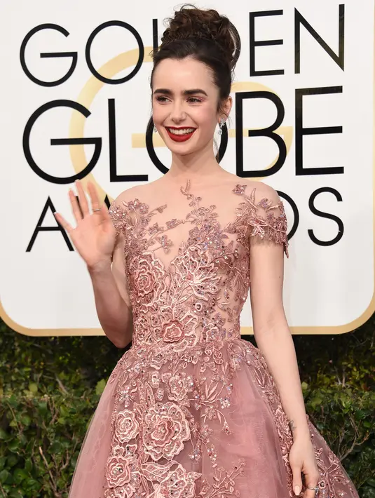 Aktris Lily Collins melambaikan tangan sambil berpose setibanya di karpet merah Golden Globe Awards di California, Minggu (8/1). Lily Collins tampil cantik seperti princess dalam balutan gaun Zuhair Murad Couture. (VALERIE MACON / AFP)
