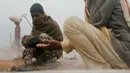 Pekerja migran India menghangatkan dirinya di atas tungku di sebuah pabrik batu bata di pinggiran Kathmandu. Ribuan pekerja migran India datang ke Nepal untuk bekerja di pabrik batu bata. (AP Photo/Niranjan Shrestha)
