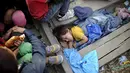 Bocah empat tahun bernama Rashida dari Suriah tidur di sela - sela balok kayu saat mereka menunggu di garis perbatasan Makedonia dan Yunani untuk masuk ke Makedonia, 20 Agustus 2015. (REUTERS/Ognen Teofilovski)