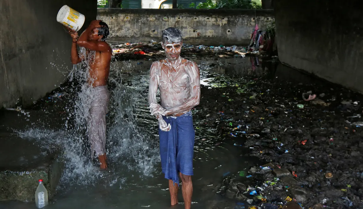 Dua laki-laki mandi di bawah sebuah jembatan di daerah kumuh di Kalkuta, India (26/5/2016). Kalkuta adalah salah satu kota pelabuhan penting di India yang merupakan ibu kota Benggala Barat. (REUTERS/Rupak De Chowdhuri)