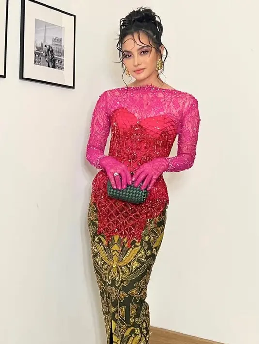 Ririn Ekawati tampil mengenakan mengenakan kebaya modifikasi warna fuschia. Kebaya buatan Maison Baaz Couture ini memiliki detail inner brokat lengkap dengan globe dipadukan korset berpayet dan bawahan kain batik slit. Ia membawa clutch hitam. [@ririnekawati]