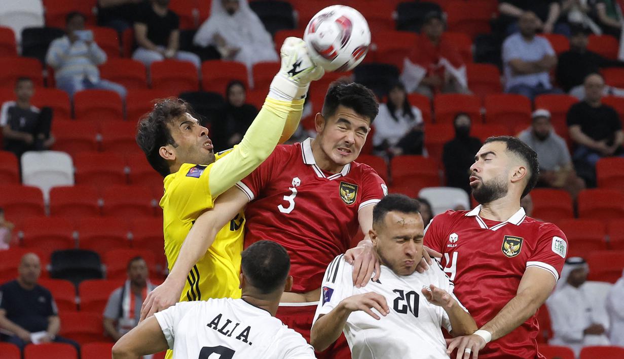 Kiper Timnas Irak, Jalal Hassan (kiri) berusaha menghalau bola dari ancaman bek Timnas Indonesia, Elkan Baggott (tengah) pada laga pertama Grup D Piala Asia 2023 Qatar di Ahmad bin Ali Stadium, Al-Rayyan, Doha, Senin (15/1/2024). (AFP/Karim Jaafar)
