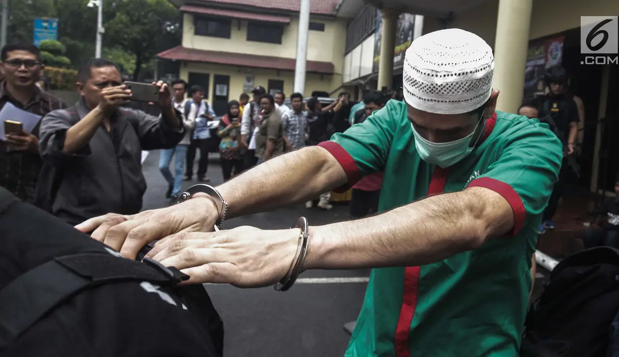 Artis Claudio Martinez dengan tangan di borgol usai rilis narkoba di Polres Jakarta Barat, Jumat (9/11). Claudio ditangkap dikediamannya di Pondok Kukusan Permai No 54 jalan KH Usman Rt 003/004 Kec Kukusan Kota Depok, Jabar. (Liputan6.com/Faizal Fanani)