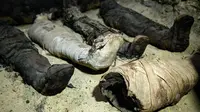 Mumi terbungkus kain linen ditemukan di ruang pemakaman di Provinsi Minya, Mesir, Sabtu (2/2). Kementerian Barang Antik Mesir mengumumkan baru menemukan tiga makam kuno dengan lebih dari 40 mumi yang terpelihara dengan baik. (AP Photo/Roger Anis)
