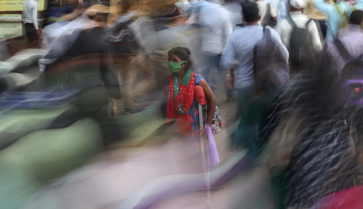 Seorang perempuan meminta sedekah saat orang-orang bergegas menaiki kereta di luar terminal kereta Chhatrapati Shivaji Maharaj di Mumbai, India,  9 November 2020. Penghitungan kasus virus corona terkonfirmasi di India, terbesar kedua di dunia, lebih dari 8,5 juta. (AP Photo/Rafiq Maqbool)